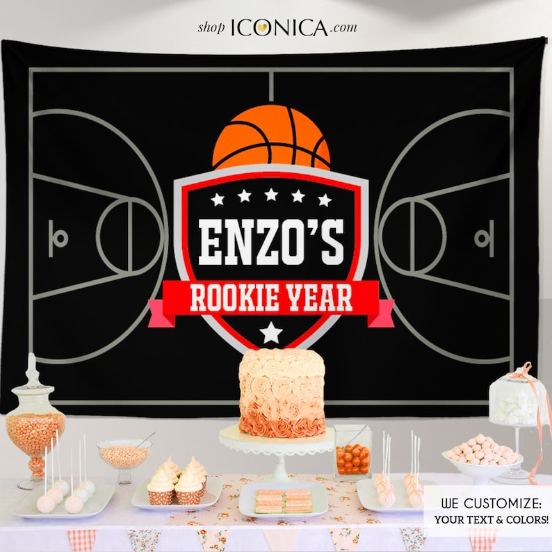 Pu&ograve; includere: Sfondo da basket in bianco e nero con uno scudo rosso e bianco con il testo "ENZO'S ROOKIE YEAR" e una grafica di pallacanestro. Lo sfondo &egrave; esposto su un tavolo con una torta, cupcake e altre decorazioni per feste.
