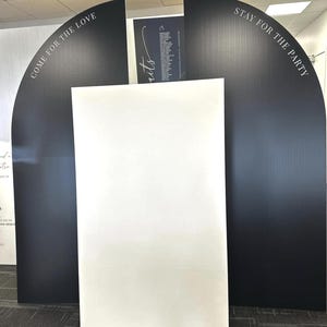 May include: A display with a white rectangular panel flanked by two black arched panels. The black panels have white text that reads "COME FOR THE LOVE" and "STAY FOR THE PARTY". The display is set up indoors.