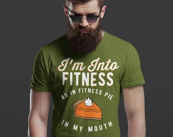 Może przedstawiać: Zielona koszulka z napisem "I'm Into Fitness As In Fitness Pie In My Mouth" i kreskówkowym obrazkiem kawałka ciasta dyniowego.