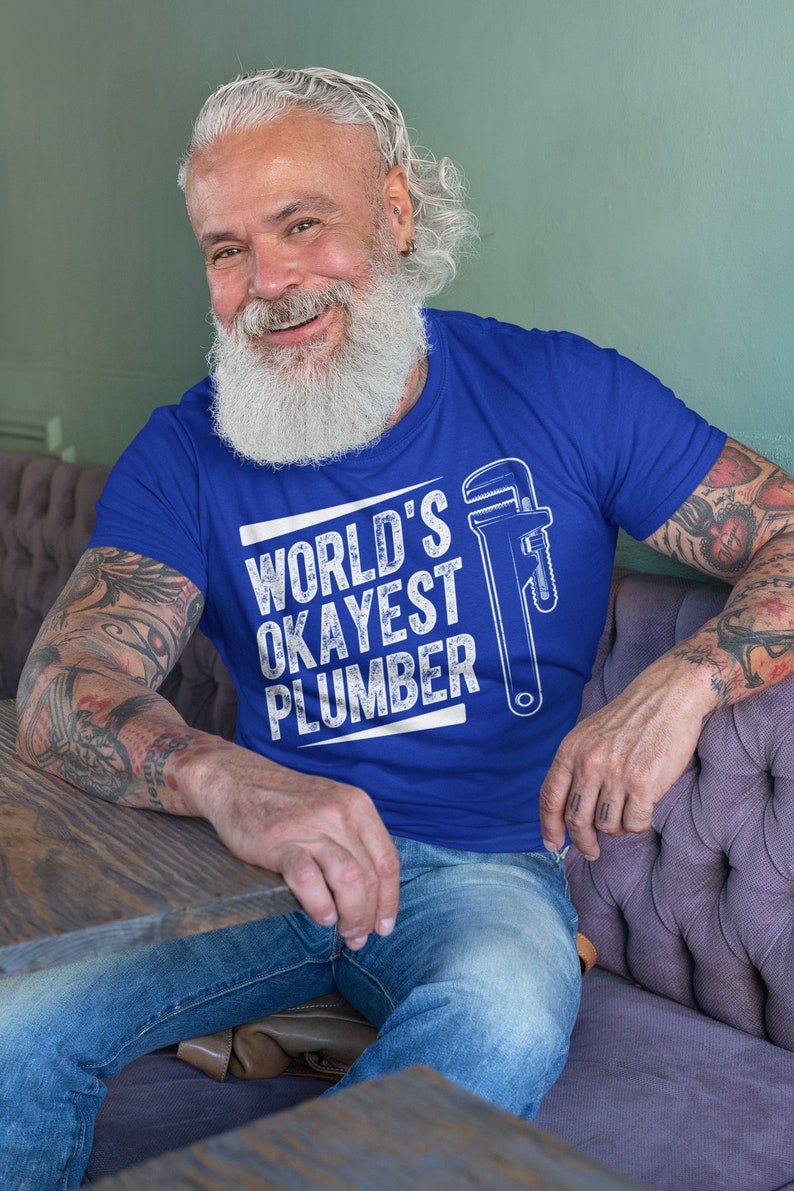 May include: A blue t-shirt with a white graphic that says "WORLD'S OKAYEST PLUMBER" and a wrench illustration.