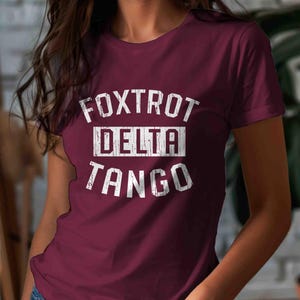 May include: A maroon t-shirt with white text that reads "FOXTROT DELTA TANGO".