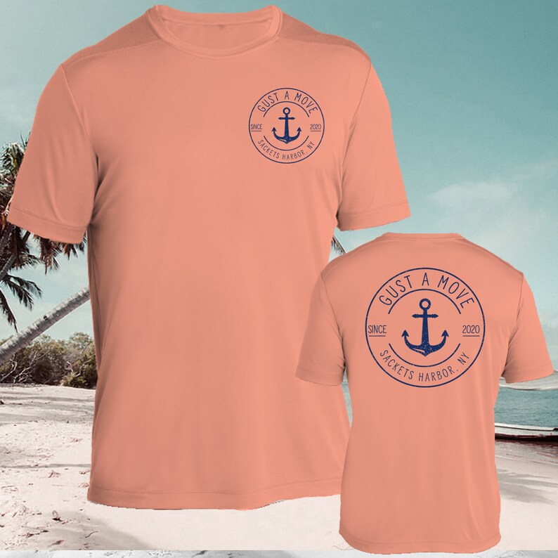 May include: Coral colored t-shirt with a navy blue anchor logo on the front and back. The logo says "GUST A MOVE SINCE 2020 SACKETS HARBOR, NY".