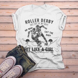 May include: White t-shirt with a black and white graphic of two roller derby skaters. The text on the shirt reads "Roller Derby Get Out of My Way Hip Whip Eat the Baby Hit Like a Girl Skate Fast Hit Hard Get Low".