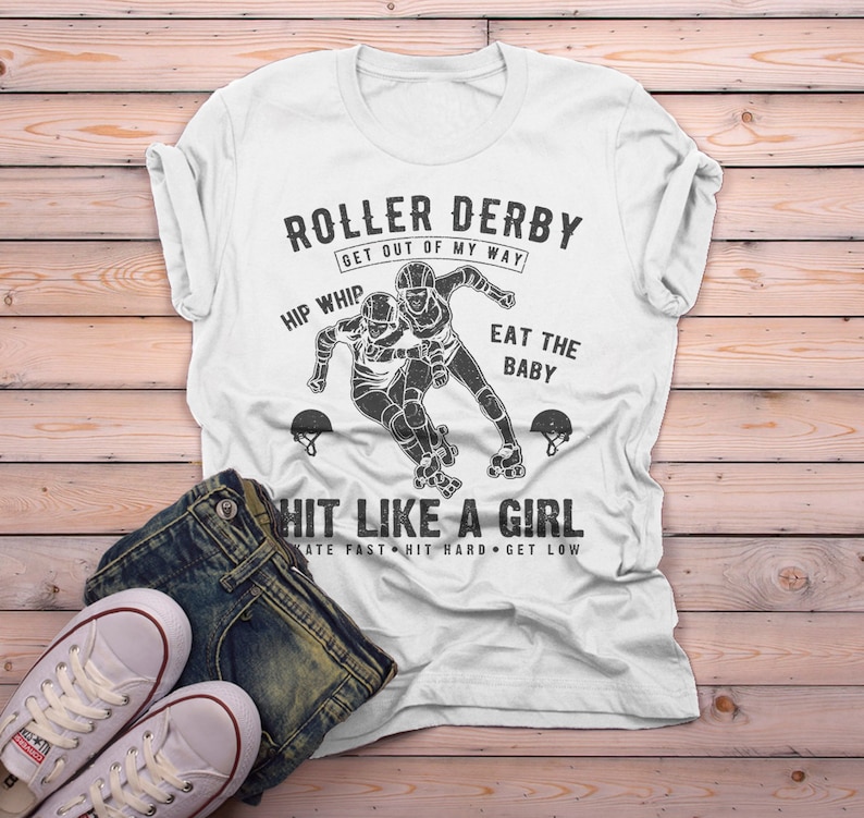 May include: White t-shirt with a black and white graphic of two roller derby skaters. The text on the shirt reads "Roller Derby Get Out of My Way Hip Whip Eat the Baby Hit Like a Girl Skate Fast Hit Hard Get Low".
