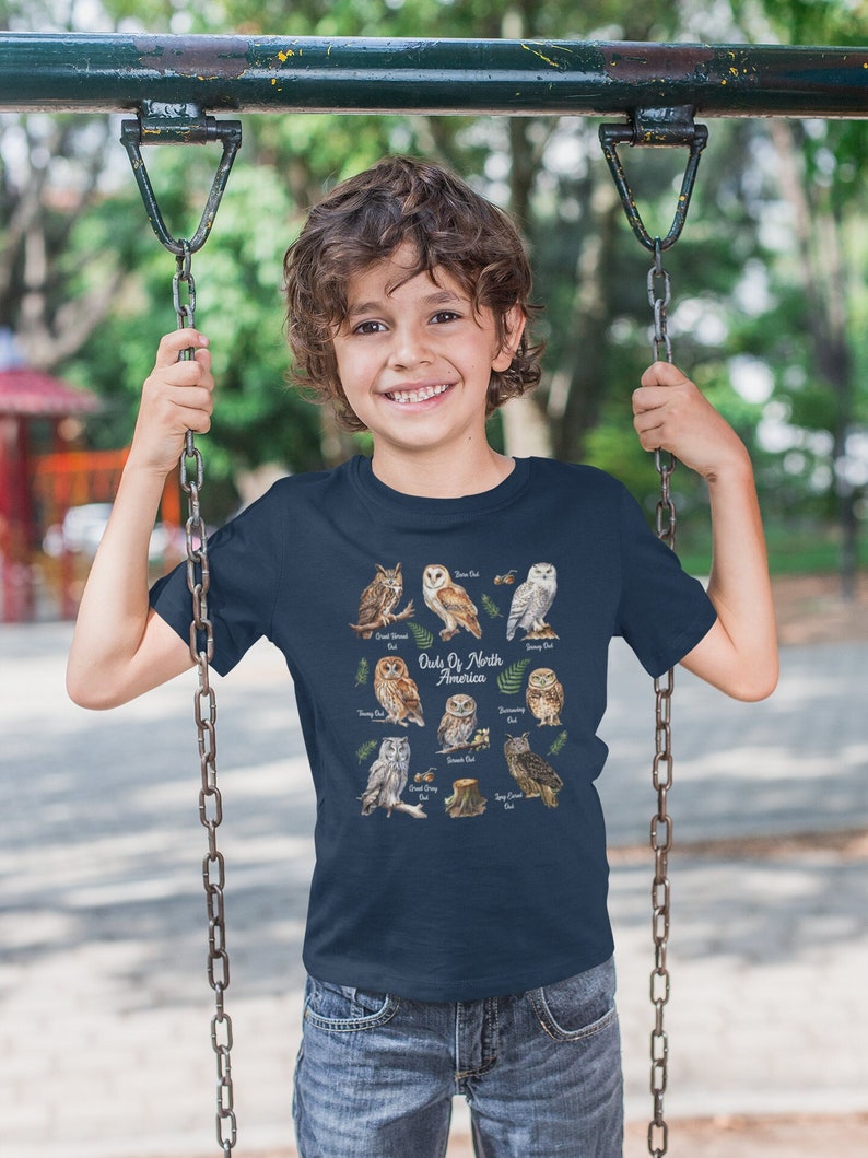 May include: A navy blue t-shirt with a graphic of different owls from North America. The text "Owls of North America" is printed on the shirt.