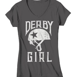 May include: A dark gray V-neck t-shirt with a white graphic of a roller derby helmet and the text "Derby Girl".