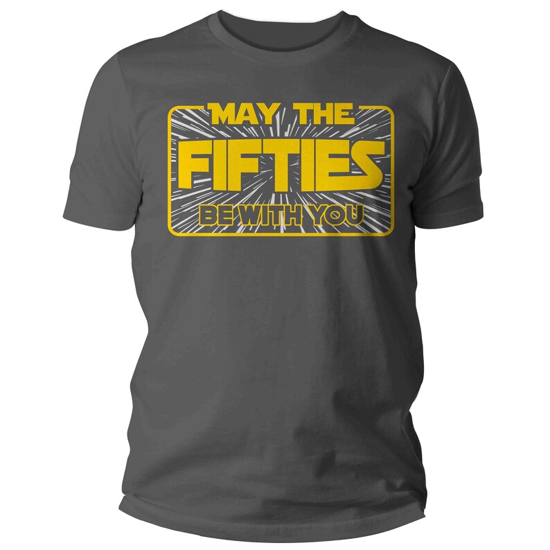 K&ouml;nnte beinhalten: Ein dunkelgraues T-Shirt mit einer gelben Grafik, auf der in einer von Star Wars inspirierten Schriftart "M&ouml;gen die F&uuml;nfziger mit dir sein" steht.