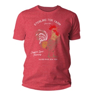 Peut inclure: T-shirt rouge chin&eacute; gris avec une illustration de coq blanc et le texte "Sterling Fox Farm Since 2017" et "Support Local Farming Salmon River, New York".
