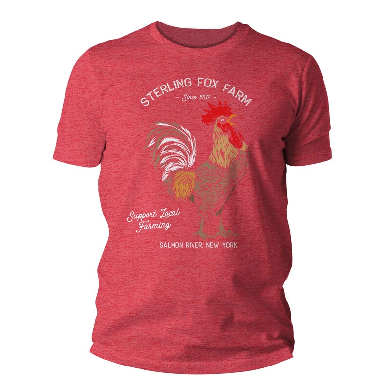 Peut inclure: T-shirt rouge chin&eacute; gris avec une illustration de coq blanc et le texte "Sterling Fox Farm Since 2017" et "Support Local Farming Salmon River, New York".
