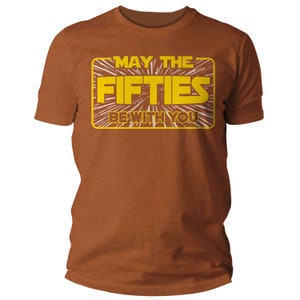 K&ouml;nnte beinhalten: Ein braunes T-Shirt mit einer gelben Grafik, auf der "M&ouml;ge die F&uuml;nfziger mit dir sein" in einer von Star Wars inspirierten Schrift steht.
