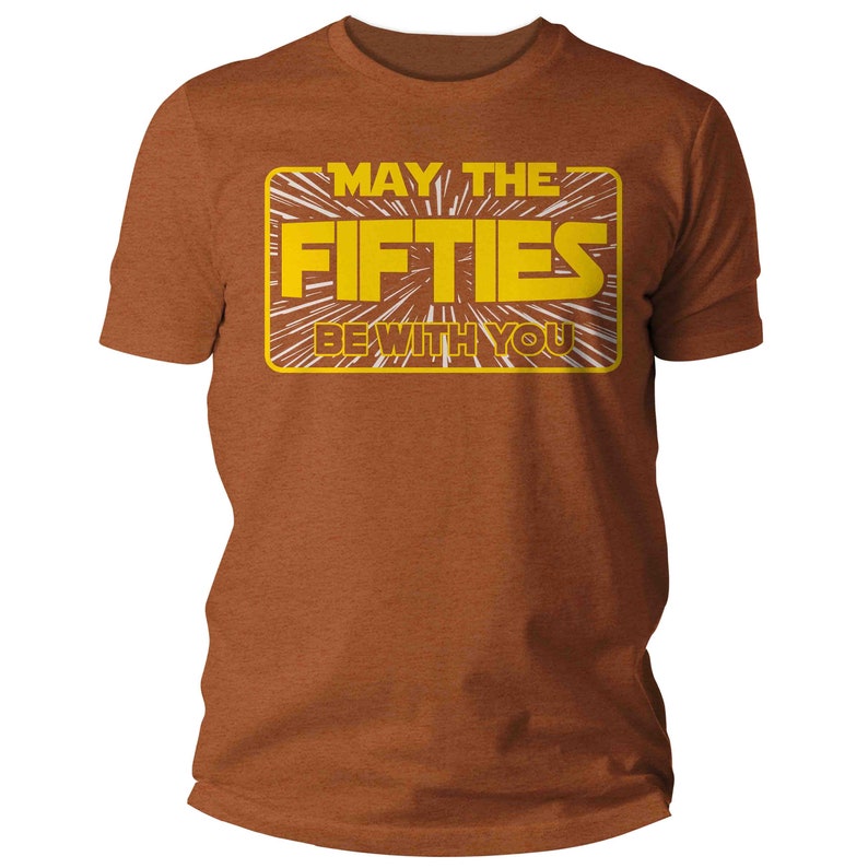 K&ouml;nnte beinhalten: Ein braunes T-Shirt mit einer gelben Grafik, auf der "M&ouml;ge die F&uuml;nfziger mit dir sein" in einer von Star Wars inspirierten Schrift steht.