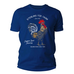 Peut inclure: Un t-shirt bleu royal avec une illustration de coq blanc et le texte "Sterling Fox Farm - Since 2017 - Support Local Farming - Salmon River, New York".