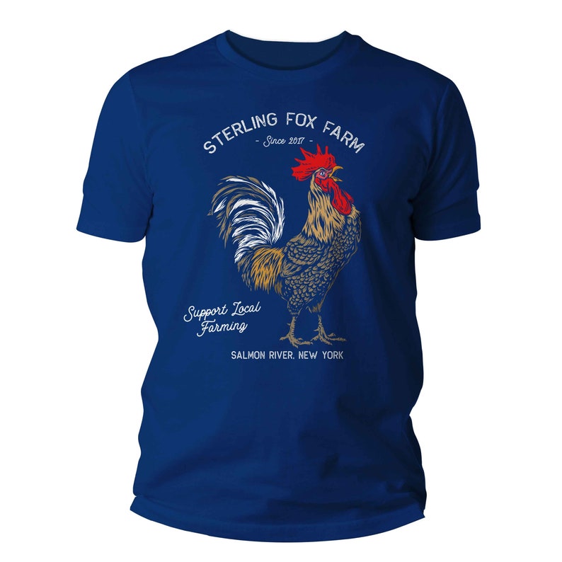 Peut inclure: Un t-shirt bleu royal avec une illustration de coq blanc et le texte "Sterling Fox Farm - Since 2017 - Support Local Farming - Salmon River, New York".