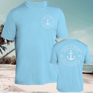 May include: Light blue t-shirt with a white anchor logo on the front and back. The logo says "GUST A MOVE" with the text "SINCE 2020 SACKETS HARBOR, NY" around the anchor.