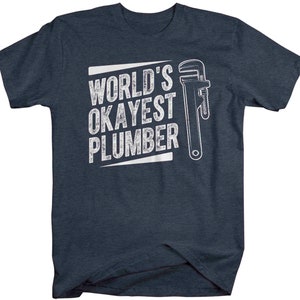 May include: A dark blue t-shirt with white text that reads "World's Okayest Plumber" and a white wrench graphic.