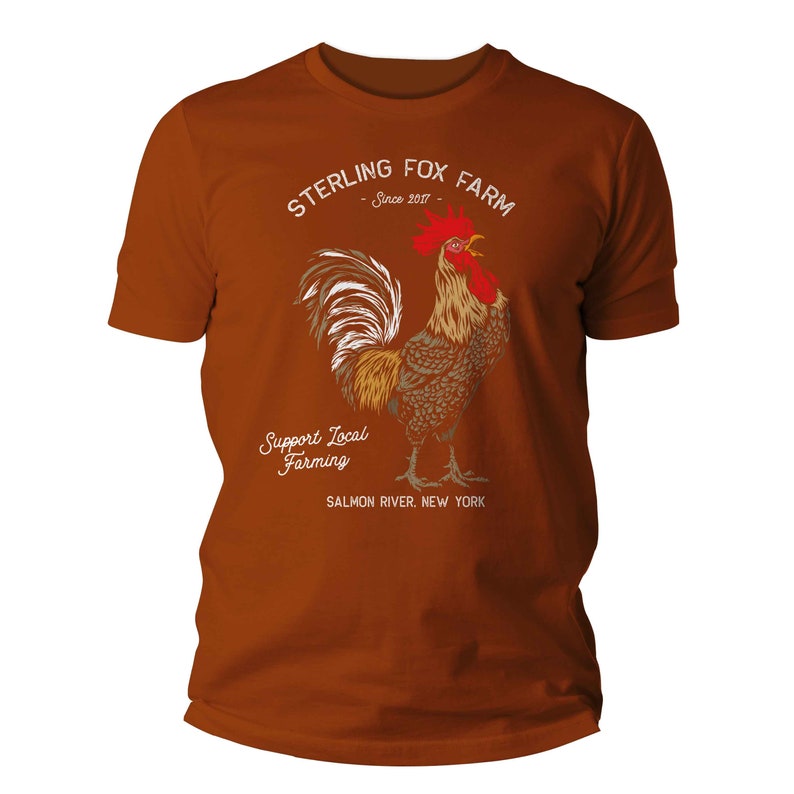 Peut inclure: Un t-shirt marron avec une illustration de coq et le texte "Sterling Fox Farm - Since 2017 - Support Local Farming - Salmon River, New York"
