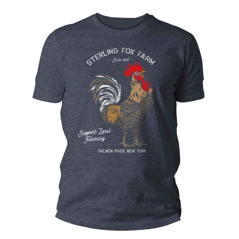Peut inclure: Un t-shirt bleu fonc&eacute; avec un graphique de coq et le texte "Sterling Fox Farm - Since 2017 - Support Local Farming - Salmon River, New York".