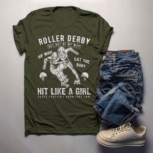 May include: A green t-shirt with a white graphic of two roller derby players. The text on the shirt reads "Roller Derby Get Out Of My Way Hip Whip Eat The Baby Hit Like A Girl Skate Fast Hit Hard Get Low".