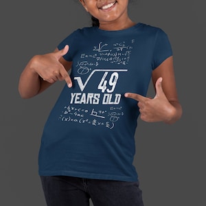 May include: A navy blue t-shirt with white text and mathematical equations. The text reads "√49 YEARS OLD".