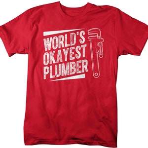 May include: Red t-shirt with white text that reads "World's Okayest Plumber" and a white wrench graphic.