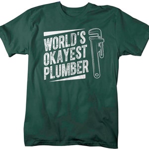 May include: A dark green t-shirt with a white graphic of a wrench and the text "World's Okayest Plumber".