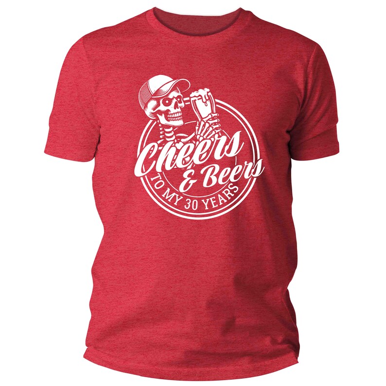 May include: Red t-shirt featuring a white graphic of a skeleton in a cap, toasting with a beer. The graphic reads "Cheers & Beers To My 30 Years" in a circular design. The shirt is made of a soft, textured material.