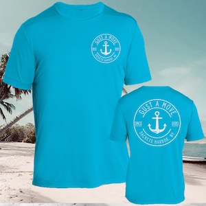 May include: A turquoise blue t-shirt with a white circle logo on the front and back. The logo says "GUST A MOVE" with an anchor and the text "SINCE 2020 SACKETS HARBOR NY".