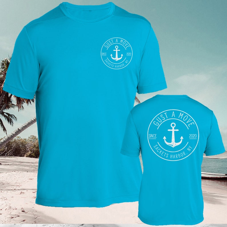 May include: A turquoise blue t-shirt with a white circle logo on the front and back. The logo says "GUST A MOVE" with an anchor and the text "SINCE 2020 SACKETS HARBOR NY".