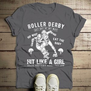 May include: Gray t-shirt with a white graphic of two roller derby players. The text reads "Roller Derby Get Out Of My Way Hip Whip Eat The Baby Hit Like A Girl Skate Fast Hit Hard Get Low".