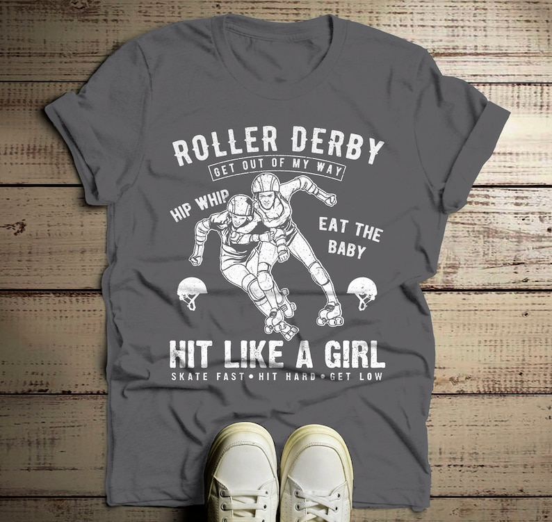 May include: Gray t-shirt with a white graphic of two roller derby players. The text reads "Roller Derby Get Out Of My Way Hip Whip Eat The Baby Hit Like A Girl Skate Fast Hit Hard Get Low".
