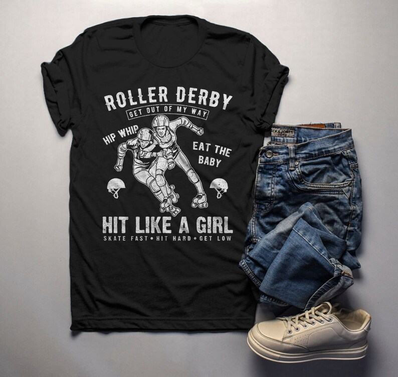 May include: Black t-shirt with a white graphic of two roller derby skaters. The text on the shirt reads "Roller Derby Get Out Of My Way Hip Whip Eat The Baby Hit Like A Girl Skate Fast Hit Hard Get Low".