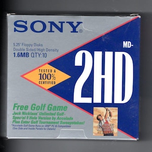 May include: A vintage Sony 5.25" floppy disk box. The box is silver and blue with the text "2HD" in large white letters. It includes the text "Free Golf Game" and a small image of a golfer. The box also states "1.6MB QTY:10".