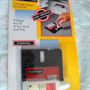 May include: Fellowes 3.5" Disk Drive Cleaning Kit in original packaging. Includes a black 3.5" cleaning disk and a white bottle of cleaning fluid. The packaging features yellow and red accents with text including 20 Applications.