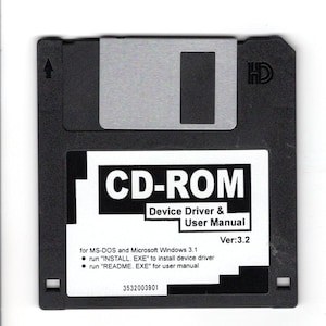 May include: A black 3.5-inch floppy disk with a silver sliding metal cover. The label reads "CD-ROM Device Driver & User Manual Ver:3.2" with instructions for MS-DOS and Windows 3.1. The disk has the HD symbol.