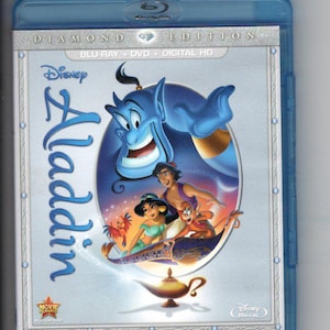 May include: A blue Blu-ray case for Disney's Aladdin Diamond Edition. The cover features the Genie, Aladdin, Jasmine, and Abu on a magic carpet. The title "Aladdin" is written in blue, with the Disney logo at the top.
