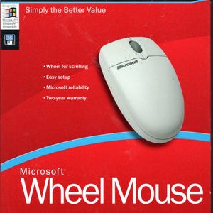 May include: A white Microsoft Wheel Mouse on a red background. The box features the Microsoft logo and the text "Simply the Better Value." Additional text includes "Wheel for scrolling," "Easy setup," and "Two-year warranty."