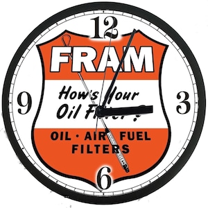 May include: A round wall clock with a black frame and a white face featuring the orange and white Fram logo. The text reads FRAM, How's Your Oil Filter?, and OIL AIR FUEL FILTERS. The clock has black hour, minute, and second hands with numbers 3, 6, 9, 12.