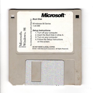 May include: A beige Microsoft Windows 98 Boot Disk floppy disk. The disk has a white label with the Microsoft logo and text including "Windows 98 Series" and setup instructions. The disk is a vintage computer accessory.