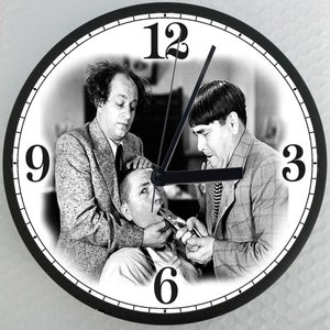 May include: A black and white clock featuring a scene from a classic comedy film. The clock face shows three men, one of whom is holding a pair of pliers near the mouth of another man. The clock face also features the numbers 12, 9, 6, and 3.