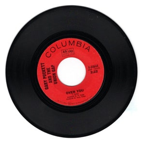 May include: A black vinyl record with a red label. The label has the text "COLUMBIA" in white letters, "GARY PUCKETT AND THE UNION GAP" in white letters, "OVER YOU" in white letters, and "4-44644 ZSP 137676 2:22" in white letters.