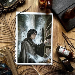 May include: A print of a person in a dark robe reaching for a jar on a shelf, with a starry background. The print is surrounded by decorative items, including a feather, bottles, and a book, all on a wooden surface.