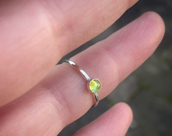 A handmade 4mm green Peridot stacking ring made of sterling silver