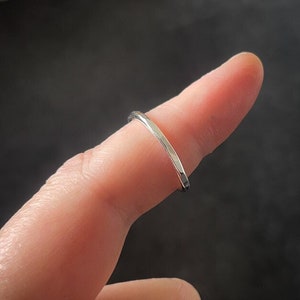 May include: A silver hammered ring worn on a finger.