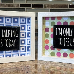 Puede incluir: Dos obras de arte enmarcadas con el texto "I'M ONLY TALKING TO JESUS TODAY". Una presenta un patrón geométrico azul y blanco, la otra un diseño de lunares de colores. Ambos marcos son blancos.