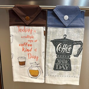 Könnte beinhalten: Zwei Küchentücher hängen an einem Gestell. Das Tuch links hat eine braune Oberseite und sagt "Today is a multiple cups of coffee kind of day". Das Tuch rechts hat eine blaue Oberseite und eine schwarz-weiße Illustration einer Kaffeekanne mit dem Text "Coffee Made My Day".