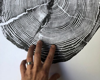 May include: Black and white print of a tree trunk cross section showing the rings. The print is on a white background.
