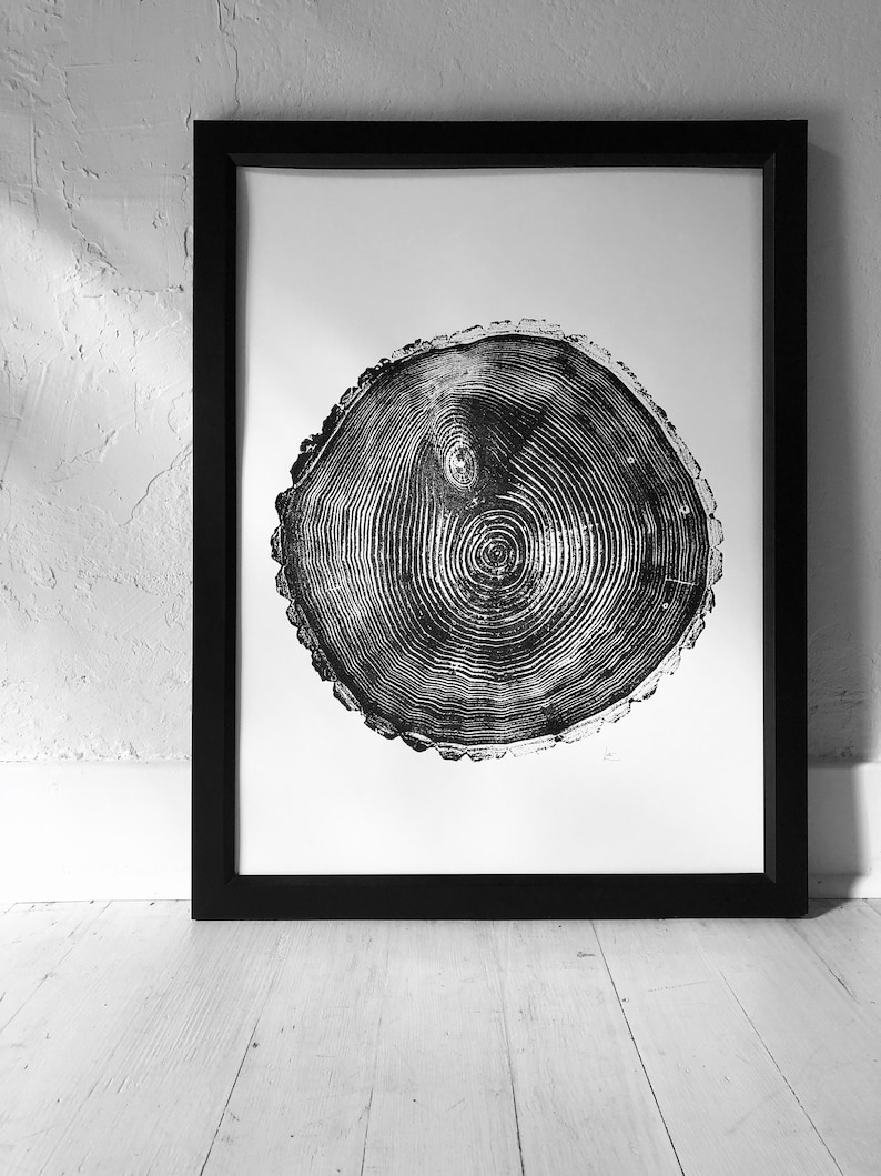 May include: Black and white print of a tree trunk cross-section, showing the rings of the tree. The print is framed in a black frame.