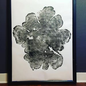 May include: Black and white print of a tree ring cross section. The print is framed in a black frame and is hanging on a wall.
