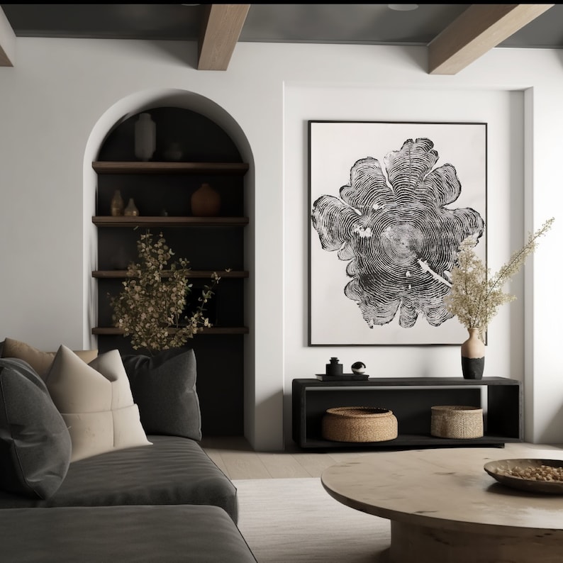 May include: A black and white print of a tree trunk cross-section hangs above a black media console with two woven baskets. A gray sofa with tan throw pillows sits in front of the console.
