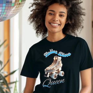 Puede incluir: Camiseta negra con un diseño de patín de ruedas dorado con detalles plateados y la frase "Roller Disco Queen" en azul. La camiseta está hecha de tela suave, adecuada para uso diario y casual.